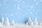 Winter Christmas minimalist background with white paper trees on blue drawing snowflakes