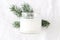 Winter, Christmas mockup-scene. Closeup of candle in glass jar with blank label. Blurred green fir tree branch, white