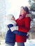 Winter, christmas and people concept - happy family son child hugs his mother in sunny winter day