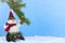 Winter Christmas scene of cute plush snowman playing on sled underneath a pine branch in artificial snow.