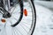 Winter in the city. Bicycle wheels in snow on blurred city background.Snowy weather.Bicycle traffic in winter.