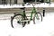 Winter in the city. Green retro bike in the snow.