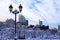 Winter city street with lantern covered with snow and hoarfrost. New Year landscape, towers, buildings, skyscrapers in winter