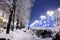 Winter city street with trees and benches covered in snow and la