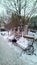 Winter cityscape with snow-covered benches, trees, architectural elements and buildings