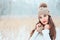 winter close up portrait of beautiful smiling young woman in knitted hat and sweater walking outdoor under snowfall