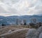 Winter coming. Picturesque foggy and moody morning scene in late autumn mountain countryside with hoarfrost on grasses, trees,