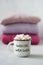 Winter cozy concept. Sweater weather text on Coffee with marshmallows in white enameled metal cup on the background of stack of