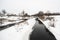 Winter daytime landscape with snow, river,trees and rustic house