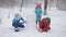 Winter family games outdoors. Mom and two daughters together mold made of snow snowman.