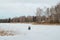 Winter fishing. Back view of fisherman catching fish on frozen, snow-covered lake in nature