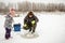 Winter fishing. The father shows the child how he fishes in winter on the ice