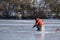 Winter fishing. A fisherman in a red jacket catches a fish