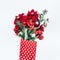 Winter flowers bunch of Amaryllis, Poinsettia and fir branches in red polka dot wrapping paper on white desktop . Top view.