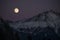 Winter forest and snow mountains under the light of the full super moon