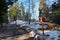 In the winter forest there is a road and a bench and a wooden signpost on the right