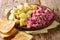 Winter German herring salad with vegetables and a side dish of boiled potatoes close-up in a plate. horizontal