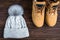 Winter gray knitted hat with boom and yellow boots on wooden background