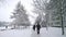 Winter is here. Snowfall in city. White snow covered tree and road. Frosty cold weather, blizzard. Chilly. Cityscape. People walk