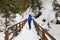 Winter hiking. Woman - hiker on pedestrian wooden bridge in  snowy mountain gorge