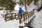 Winter hiking. Woman - hiker on pedestrian wooden bridge in  snowy mountain gorge