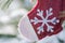 Winter holiday decoration concept: snowflake crochet Christmas stocking and frozen snow covered pine tree twigs in forest