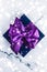 Winter holiday gift box with purple silk bow, snow glitter on marble background as Christmas and New Years presents for luxury