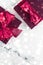 Winter holiday gifts with cherry silk bow and glowing snow on frozen marble background, Christmas presents surprise