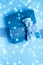 Winter holiday gifts and glowing snow on frozen blue background, Christmas presents surprise