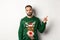 Winter holidays and christmas. Displeased and grumpy guy complaining, wearing funny sweater, pointing finger at upper