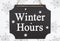 Winter Hours message on a retro hanging chalkboard with snowflakes