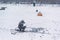 Winter ice fishing, lake, frosty day. Fisherman engaged in ice fishing in the pond of the city Park