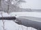 Winter lake shore with opened water in ice under channel tube