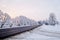 Winter landscape. Asphalted rural road at an early, cold winter sunrise - image