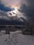 Winter landscape in Black Forest with snowshoe hiking trail surrounded by frozen trees and sun shining through the clouds.