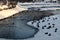 Winter landscape in the city park. Rumia, Poland. Ducks in frozen and snowy park pond.