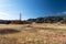 Winter landscape of dried grasses on an open plain, low mountains with power line