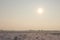 Winter landscape with a field and the sun