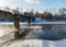 Winter landscape, fog on the river, bridge silhouette in the background, beautiful white frost covering trees and grass on the