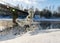 Winter landscape, fog on the river, bridge silhouette in the background, beautiful white frost covering trees and grass on the