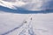 Winter landscape, footprints path and people walking in snow valley in bright sunny day