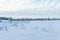 Winter landscape with frozen grass, snowy field and bare trees