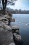 Winter landscape. Granite, rocky shore by the lake in a city park.