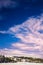 Winter landscape with high sky and large white clouds. Snowy plain with pines and firs in the mountains on a calm day.