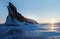 Winter landscape on Lake Baikal. Rays of the rising sun against the backdrop of a huge rock.