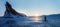 Winter landscape on Lake Baikal. Silhouette of a cyclist in the rays of the rising sun against the backdrop of a huge rock.