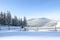 Winter landscape. The meadow overlooks the mountains, the forest with trees covered with snow and the blue sky. On the path near