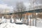 Winter landscape with a road and trees in the city against the background of the surface metro, houses on the outskirts