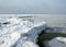 Winter landscape by the sea, snowy, interesting ice shapes on the sea shore, dunes covered with a white layer of shining snow