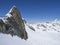 Winter landscape with sharp mountain peak and snow covered slopes and pistes with skiers enjoying spring sunny day at